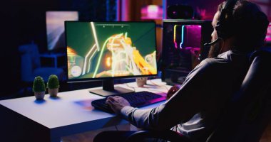 Adam gece geç saatlerde bilgisayar masasında arkadaşlarıyla FPS video oyunu oynayarak rahatlıyor. Oyuncu takım arkadaşlarıyla iletişim kuruyor, online çok oyunculu birinci şahıs nişancılarda düşmanları vuruyor.