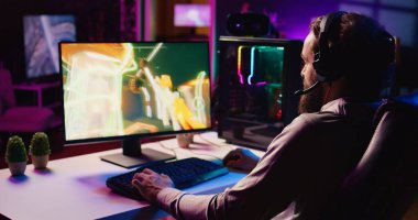 Adam takım arkadaşlarıyla iletişim kurmak için kulaklık mikrofonu kullanıyor. FPS video oyunu oynarken lazer mermi atıyor. Oyuncu oyundan zevk alırken internet arkadaşlarıyla sohbet ediyor