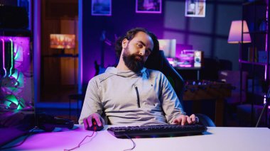 Uykulu adam bütün gün video oyunu oynadıktan sonra yorgun hissediyor, uyanık kalmak için çabalıyor, bağımlılığı kontrol edemiyor. Oturan oyuncu çevrimiçi oyunda yarışırken koltukta uyuyakalıyor