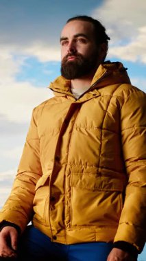 Dikey Video Gururlu kaşif, dağın zirvesinde kollarını kaldırıp, farkındalık içinde durarak başarının tadını çıkarıyor. Gezgin çarpıcı manzaraya hayran ve heyecan dolu engin gökyüzüne