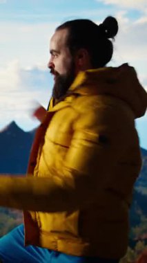 Dikey Video Heyecanlı Gezgin, dağın zirvesine tırmanıp doğanın panoramik güzelliğinin tadını çıkararak zafer kazanarak kollarını kaldırıyor. Uçsuz bucaksız gökyüzüne ve uçsuz bucaksız manzaraya hayranlık duyuyorum.