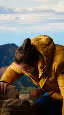 Dikey Video Gururlu kaşif, engebeli tepeler ve dramatik bulutlarla çevrili yüksek rakımlı bir dağın zirvesinde kutlama yapıyor. Zafer pozu başarıya tırmanmanın heyecanını yakalar. Kamera B.