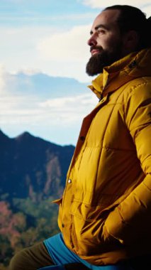 Dikey Video Yürüyüşçüsü vahşi doğada yürümenin zorluğunu kucaklıyor, panoramik dağ manzarasından güç ve açık hava macerasının ödülü olarak zevk alıyor. Macera Avcısı