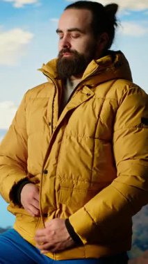 Dikey Videolu Kararlı Gezgin, panoramik manzaranın macera ve kişisel gelişimi temsil ettiği bir dağ zirvesinin yalnızlığının keyfini çıkarıyor. Yürüyüşçü rüzgarlı dağın tepesinde üşüyor. Kamera B.