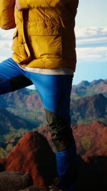 Dikey Video Belirleyici dağcı gökyüzüne ve kayalık dağ tepelerine bakıyor, limitlerin ötesine geçmek için gereken esneklik ve hırsı yansıtıyor. Nefes kesici ufuk çizgisi manzarası maceraya ilham verir. Kamera.