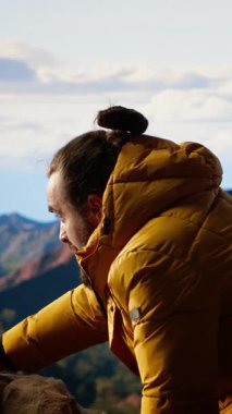 Dikey video doğa aşığı dağın zirvesinde taze temiz havayı soluyor özgürlüğün ve maceranın tadını çıkarıyor. Gezgin başarılarıyla gurur duyuyor, manzaralı vadiye tepeden bakıyor.