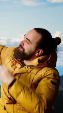 Dikey Videolu Kararlı Maceracı panoramik dağ manzarasından zevk alıyor, doğanın ve yükselen zirvelerin nefes kesici bir nefes kesici yarattığı tepenin arka planındaki muhteşem manzarayla selfie çekiyor.