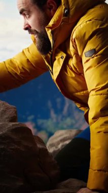 Dikey video doğa aşığı dağın zirvesinde taze temiz havayı soluyor özgürlüğün ve maceranın tadını çıkarıyor. Gezgin başarılarıyla gurur duyuyor, manzaralı vadiye tepeden bakıyor.