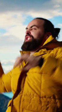 Dikey Videocu, nefes kesici bir dağ zirvesinde manzaranın keyfini çıkararak, başarılı bir yürüyüşten sonra mutlu ve tatmin edici bir şekilde kutluyor. Gururlu yürüyüşçü kararlılığı somutlaştırır