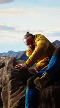 Zirvede duran Dikey Video Kararlı Dağcı huzurlu bir başarı anının tadını çıkarıyor. Uçsuz bucaksız gökyüzü, dağ sıraları ve temiz hava özgürlüğün, refahın ve keşiflerin özünü vurguluyor. Kamera.