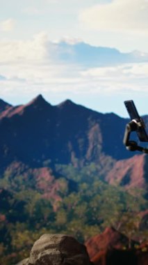 Dikey Görüntü İçeriği Yaratıcısı, dağlarda bir video bloğu kaydeder ve açık hava macerasını izleyicileriyle paylaşır. Erkek yürüyüşçü her zaman dengeleyici bir tripoda monte edilmiş bir akıllı telefona bağlıdır. Kamera A.