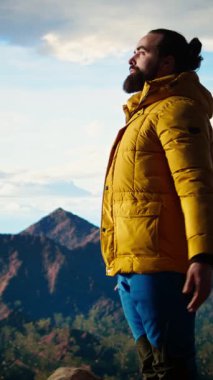 Dikey Görüntü Huzurlu kâşifi, stres atmak için meditasyon yapıyor. Dağın tepesinde rahatlık ve denge için dinleniyor. Genç gezgin, dikkat çekmek için meditasyon yapıyor.