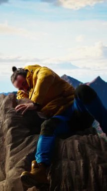 Dikey Videolu Genç Gezgin kalın giysiler içinde derin bir tatmin duygusuyla zirveye ulaşır, çok yorgun ama başarısından gurur duyar. Maceracı bir hedefe ulaşıyor. Kamera A.