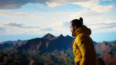 Yürüyüşçü dağların panoramik manzarasına hayran olmak için bir dakikasını ayırır, uzaklığa ve manzaraya bakar. Temiz hava, manzaralı arka plan ve bir kaşif için huzurlu bir ortam. Kamera A.