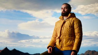 Gururlu kaşif, dağın zirvesinde kollarını kaldırıp, farkındalık içinde durarak başarının tadını çıkarıyor. Gezgin muhteşem manzaraya hayran ve yürüyüş heyecanı için uçsuz bucaksız gökyüzüne. Kamera B.
