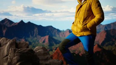 Erkek kaşif yüksek rakımlı vahşi doğanın yalnızlığını kucaklıyor, temiz hava ve manzaralı bir arka plan için dağın tepesine tırmanıyor. Doğadaki farkındalık ve rahatlama. Kamera A.