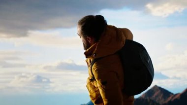 Erkek yürüyüşçü derin bir nefes alır, temiz dağ havası alır manzaradan memnun hisseder, vahşi doğaya hayran kalır. Nefes kesici manzara farkındalık ve rahatlamaya ilham verir. Kamera B.