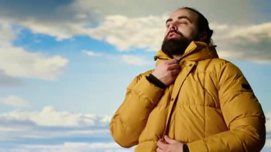 Dağ yürüyüşçüsü, zirveye tırmandıktan sonra geniş bir tepe ve gökyüzü manzarasıyla ceketinin fermuarını çekerek vahşi doğada gezinti macerasını kucaklıyor. Açık hava keşfi. Kamera B.