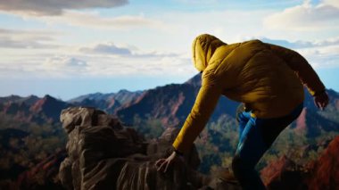 Genç maceracı telefonunu kullanarak dağın tepesinde fotoğraf çekiyor ve başarının anını yakalıyor. Doğa aşığı yürüyüşçü dağ sırasına tırmanıyor ve zirvede oturuyor. Kamera A.