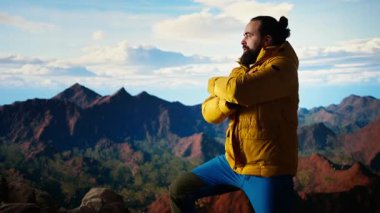 Heyecanlı maceracı, azim ve dayanıklılık ruhunu somutlaştırarak dağın zirvesine ulaşmasını kutluyor. Yürüyüşçü bir dağ silsilesinin panoramik manzarasının tadını çıkarıyor. Kamera A.