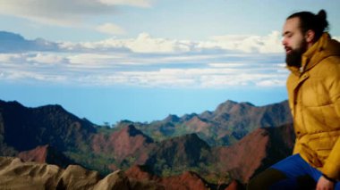 Yürüyüşçü dağların panoramik manzarasına hayran olmak için bir dakikasını ayırır, uzaklığa ve manzaraya bakar. Temiz hava, manzaralı arka plan ve bir kaşif için huzurlu bir ortam. Kamera B.