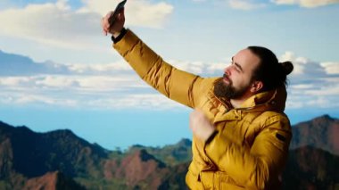 Azimli maceracı, doğanın ve yüksek zirvelerin nefes kesici bir manzara yarattığı tepenin arka planındaki muhteşem manzarayla selfie çekerek panoramik dağ manzarasının tadını çıkarıyor. Kamera B.