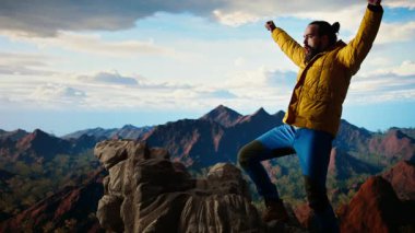 Trekker kollarını dağ sırasının tepesinde heyecan içinde uzatıyor, tırmanma başarısından gurur duyuyor ve tatmin oluyor. Genç yetişkinler azim ve hırslarını sergilerler. Kamera A.