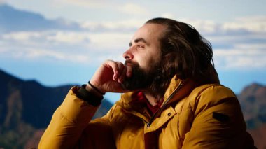 Erkek aktif gezgin, güzel dağ sırası vadisine hayran ama soğuk rüzgarlarla mücadele ediyor. Kamp alanındaki tehlikeli rüzgarlarla mücadele ediyor. Doğada gezinti tutkusu. Kamera B.