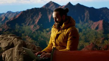 Genç kaşif dağın tepesinde çalışmaya devam ediyor. Her yerde internet var. Tepe zirvesinde küresel bağlantının ve verimliliğin tadını çıkarıyor. Yürüyüş sırasında yüksek hızda güçlü sinyal. Kamera B.