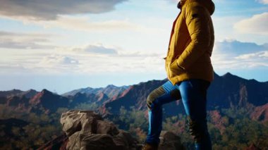 Yürüyüşçü dramatik dağ zirveleri ve bulutların panoramik manzarasına bakar, maceranın heyecanını ve azmin ödüllerini hisseder. Yolculuk gücü ve kişisel gelişimi temsil ediyor. Kamera A.