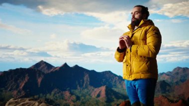 Genç kaşif dağın zirvesine ulaşıyor ve zirvede meditasyon yapıyor, sakin ve dikkatli bir şekilde zen meditasyonu yapıyor. Keyifli yürüyüşçüler doğayı özen gösterdikleri için severler. Kamera A.