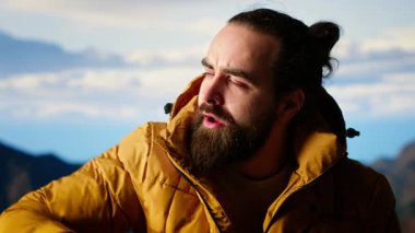 Kaşif, bir dağ zirvesine ulaşmanın heyecanını kucaklıyor ve dinleniyor, temiz havayı ve panoramik güzelliği hissediyor. Yürüyüşçü heyecanlı ve yorgun, kendini geliştirme ve hedefleriyle gurur duyuyor. Kamera B.