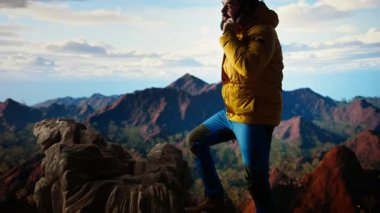 Trekker yüksek rakımlı manzaranın tadını çıkarıyor ve bir telefon görüşmesi yapıyor, panoramik dağ manzarası ve gevşek hava rahatlama için mükemmel bir manzara sağlıyor. Akıllı telefonunda güçlü bir sinyal kullanıyor. Kamera A.