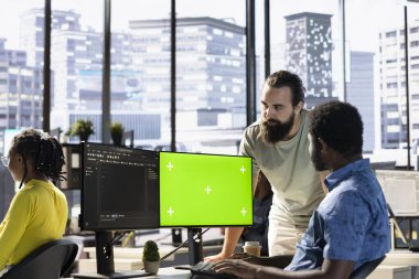 Yeşil ekranda yazılım hata ayıklaması yapan programcı, iş arkadaşından yardım istiyor, kod satırlarındaki hataları kontrol ediyor. Çalışan, meslektaşı tarafından desteklenen, model bilgisayardaki kodlama hatalarını düzeltir