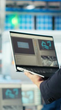 Dikey video güneş panelleri enerji sistemlerini incelemek ve güneş enerjisini kullanan yeni teknolojiler geliştirmek için dizüstü bilgisayar kullanan bitki uzmanları. Fotovoltaik fabrikası araştırmacısı geliştirmek için defter üzerinde çalışıyor