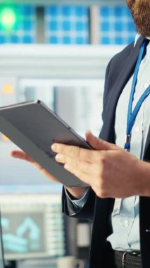 Dikey video Photovoltaics fabrikası mühendisi güneş panelleri verimliliğini arttıran bir tablet tutuyor. Güneş panelleri daha ucuz ve daha sürdürülebilir güneş çözümleri kullanan fabrika işçisi üretiyor.