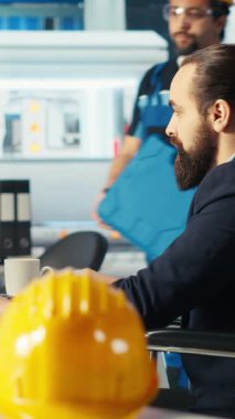 Tekerlekli sandalyede engelli olan dikey video Photovoltaics fabrikası müdürü işçiye iş veriyor. Güneş panelleri parapleji ile birlikte fabrika denetleyicisi dahil çalışma alanı çalışanı, kamera B ile konuşuyor