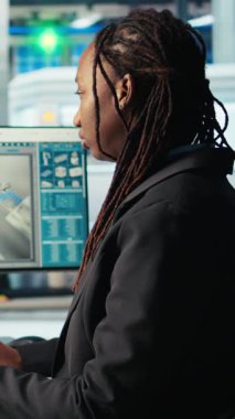 Dikey video Photovoltaics fabrika programcısı güneş panelleri verimliliğini arttırmak için bilgisayarda kodlama yapıyor. Afrika kökenli Amerikalı yazılım geliştirici güneş panellerinde çalışıyor fabrika üretiyor, araştırma yapıyor, kamera yapıyor.