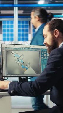 Dikey video Photovoltaics fabrika işçisi sistem performansını izliyor, kahve içiyor. Güneş panelleri imalat fabrikası çalışanı enerji üretimini izlemek için bilgisayar kullanırken içecekten keyif alıyor ve
