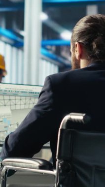 Tekerlekli sandalyedeki paraplejili dikey video Photovoltaics fabrikası çalışanı güneş paneli imalatının performansını izlemek için bilgisayarı kullanıyor. Güneş santrali makinelerini denetleyen engelli kişi