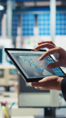 Tablet üzerinde dikey video Photovoltaics fabrikası teknisyen izleme sistemi performansı. Güneş panelleri enerji üretimini ve verimliliğini takip etmek için aygıt kullanan fabrika işçisi üretiyor.