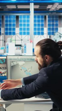 Dikey video Photovoltaics fabrika müdürü robot silahlarının performans belgelerini inceledi ve güneş panellerini montaj hatlarına yerleştirdi. Denetmen, güneş santrali makinelerinin denetim veri dosyalarını okuyor