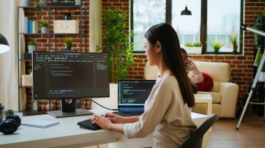 Asyalı programcı, dijital çalışma alanında çalışan çift monitörlerde kullanıcı arayüzü dizaynı için kod yazarken görüldü. Kadın kodlayıcı yazılım mühendisliği ve ön uç geliştirme üzerinde çalışıyor. Kamera A.