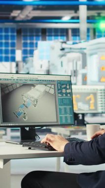 Fotovoltaik fabrikasındaki dikey video mühendisi arızalı sistemleri teşhis etmek için bilgisayar ekranı kullanıyor. Güneş panelleri bilgisayar masasında çalışan fabrika işçisi üreterek sistemin işlevsel güvenilirliğini koruyor