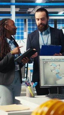 Fotovoltaik fabrikasında çalışan neşeli müfettişlerin arıza teşhisi koyan dikey video portresi. Güneş panellerini inceleyen mutlu yöneticilerden oluşan bir ekip dinlenme süresini azaltmak için fabrika üretiyor.