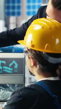 Dikey video güneş paneli imalat fabrikası yöneticisi PC 'de mühendislere yeni güneş enerjisi sistemleri için prototiplerin nasıl geliştirileceğini gösteriyor. Takım lideri teknisyene yeni fotovoltaik materyallerden bahsetti