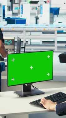 Dikey video Photovoltaics fabrika işçisi yeşil ekran PC 'deki sistem performansını izliyor. Güneş panelleri enerji üretimini izlemek için krom anahtar bilgisayar kullanan fabrika çalışanı üretiyor.