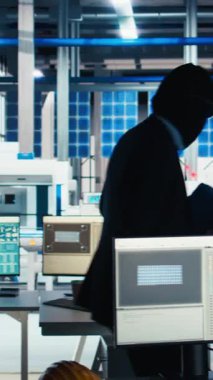 Dikey video maskeli hacker gece gizlice güneş paneli tesisine giriyor, USB çubuğunu bilgisayara yerleştirip gizli üretim verilerini çalıyor. Fotovoltaik fabrikasındaki hırsız şirket dosyalarını alıyor.
