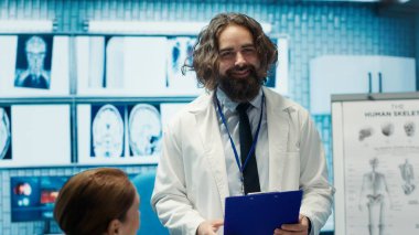 Uzman doktorlar, bir toplantıda meslektaşlarıyla sağlık kayıtlarını, etkili tedavi stratejilerini koordine eden klinik personelini tartışıyor. Özel bir tesisteki doktorlar test sonuçlarını inceliyor. Kamera A.