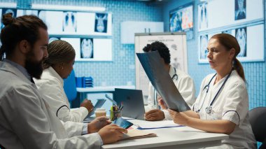 Personelle toplantı sırasında test sonuçları ve radyografiyi analiz eden özel bir klinikte tıbbi uzman. Lisanslı sağlık görevlileri hastalık önleme için tedavi seçeneklerini araştırıyor. Kamera B.